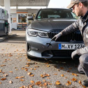Ein Sachverständiger deutet präzise auf ein gebrochenes Kunststoffgitter im verformten Stoßfänger eines Autos.